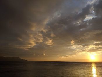 Scenic view of sea against dramatic sky during sunset