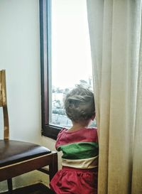 Rear view of woman looking through window