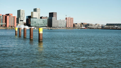 Sea by cityscape against clear sky