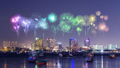 Firework display over illuminated buildings in city at night