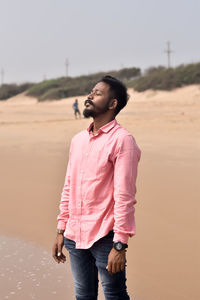 Young man looking away while standing on land