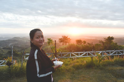 Portrait of young woman standing against sky