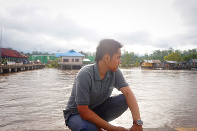 Man sitting on shore against sky