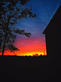 Silhouette trees on landscape against sky at sunset