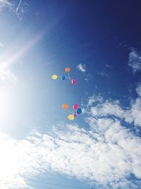 Low angle view of colorful balloons flying against blue sky