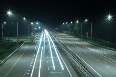 Night road with long red and white light strips from the headlights of cars.