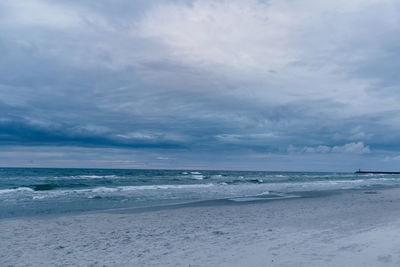 Scenic view of beach against cloudy sky