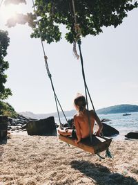 Man sitting on shore against sky