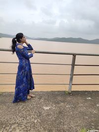 Woman standing on railing against sea