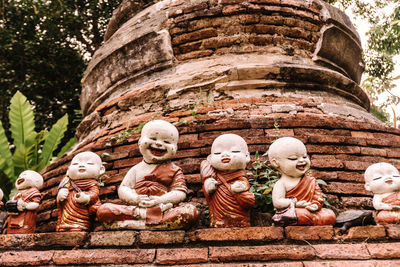 From below of ancient small stone statues of buddha on roof of temple in thailand