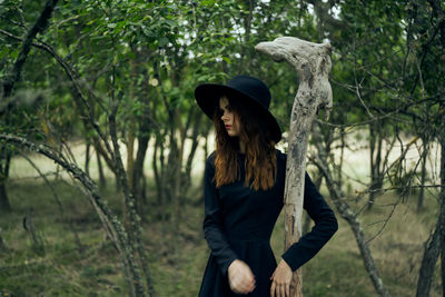 Woman standing by tree in forest