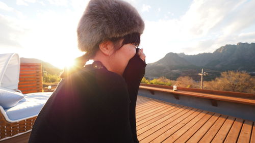 Portrait of young woman standing on railing against mountains