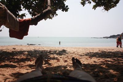 Low section of people on beach against sky