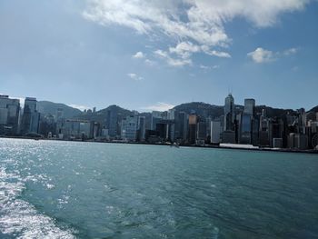 Sea by cityscape against sky