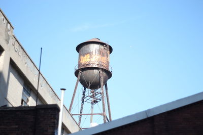 Low angle view of water tower on building against clear sky