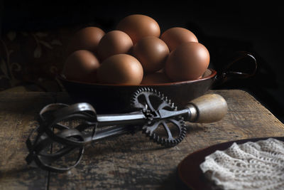 Fram house fresh eggs on a wooden table with iron whisk