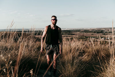 Full length of young man standing on field against sky