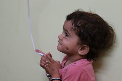 Cute girl with cable standing against wall