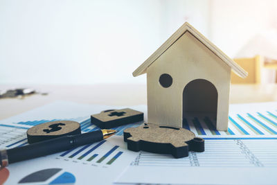 High angle view of graphs with model home and pen on table