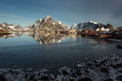 Scenic view of lake by snowcapped mountains against sky