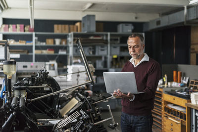 Man in a printing shop looking at laptop