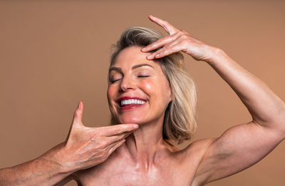 Close-up of shirtless senior woman against wall
