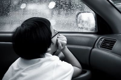 Side view of girl looking through window while sitting in car