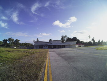 Empty road by building against sky