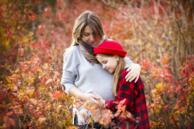 Mother embracing with daughter against plants