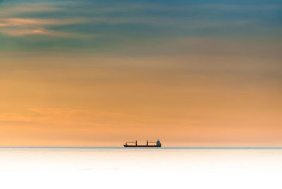 Boat on sea against sky during sunset