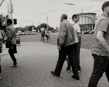 Rear view of people walking on street in city