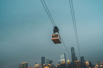 Low angle view of overhead cable cars and buildings against sky
