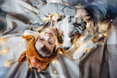 The boy and his dog are sitting under the christmas tree. australian shepherd. holiday mood