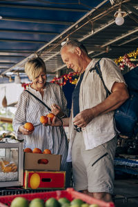 Senior couple buying oranges from market on vacation