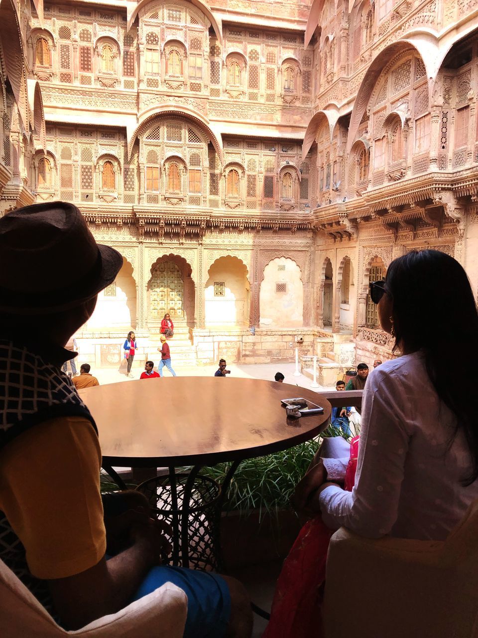 REAR VIEW OF PEOPLE SITTING AT HISTORIC BUILDING