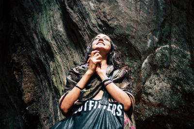 Low angle view of woman standing on rock against trees