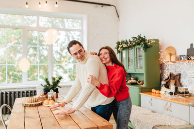 Young man and woman romantic couple couple hug at the kitchen while coocking and backing