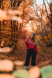 Full length of young woman standing in forest