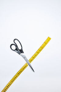 High angle view of tailoring tools scissors, and yellow tape measure over white background. diy.