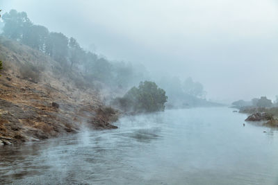 Scenic view of waterfall in foggy weather