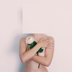 Topless woman face covered with paper against white background