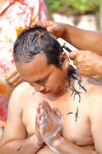 Cropped image of monk cutting hair of man during ordination