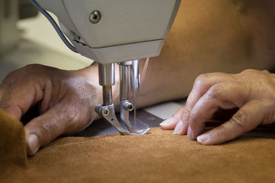 Cropped image of worker sewing fabric at workshop
