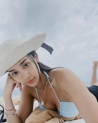 Portrait of young woman wearing hat against sky