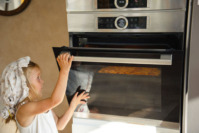 Little girl cooking pizza in the kitchen