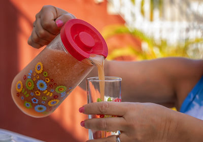 Woman pours juice into a glass.