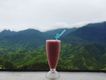 Close-up of drink on table against mountains