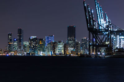 Illuminated modern buildings against sky at night