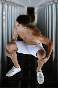 Upside down image of shirtless young man jumping below bridge