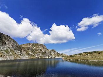 Scenic view of lake by mountains against sky